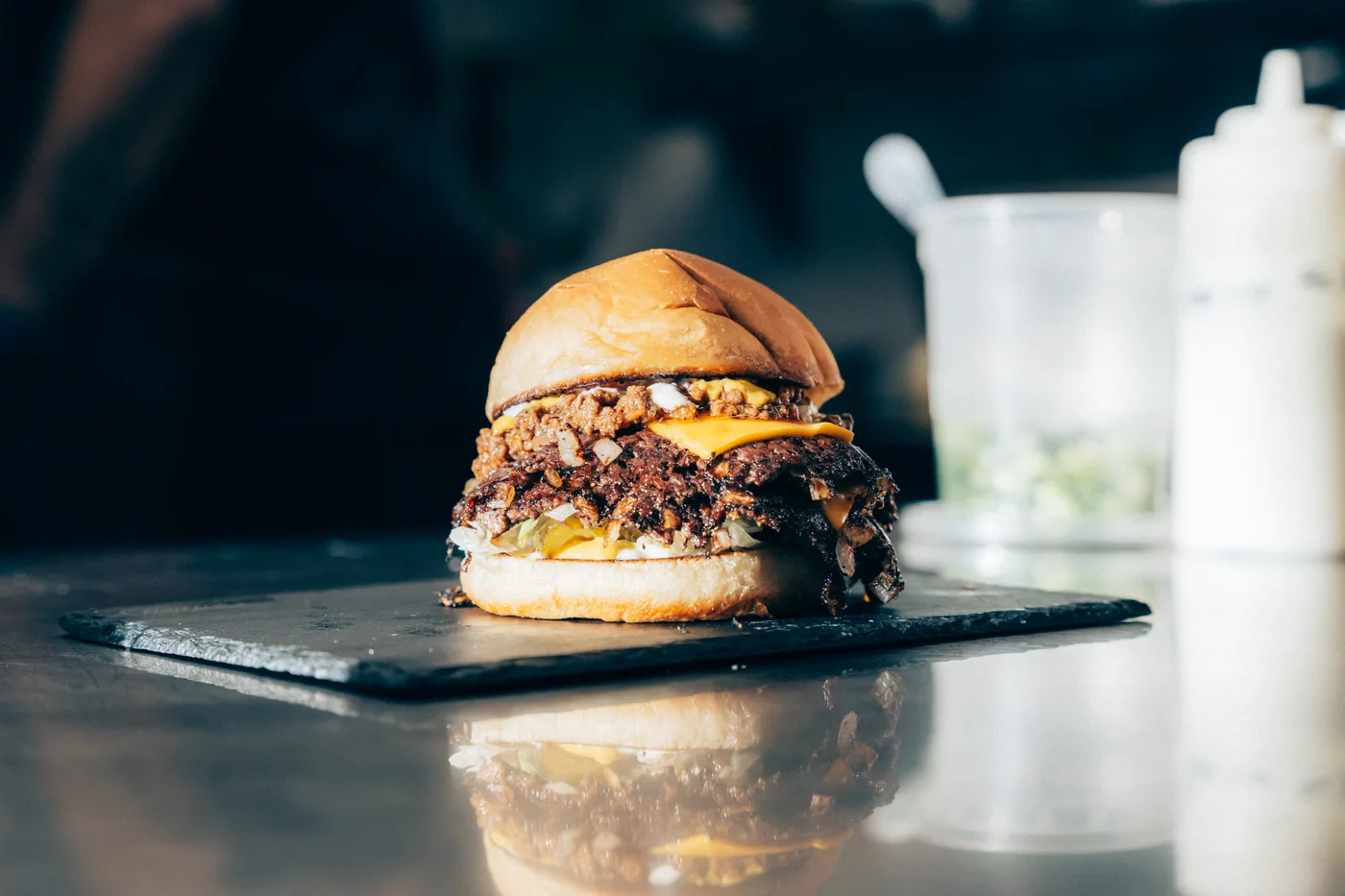A double smash burger with caramelised onions on a slate board